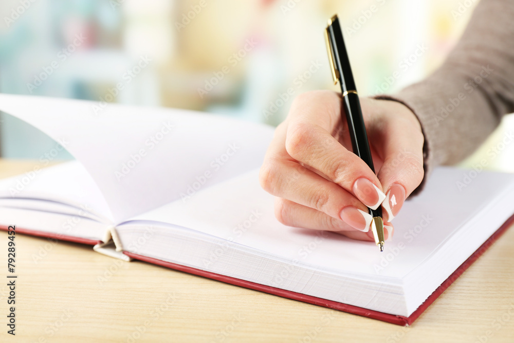 Female hand with pen writing on notebook, closeup Female hand with pen writing on notebook, closeup