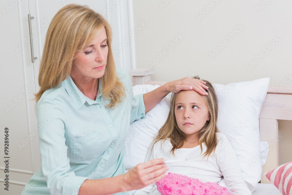 Fototapeta premium Mother measuring her daughters temperature
