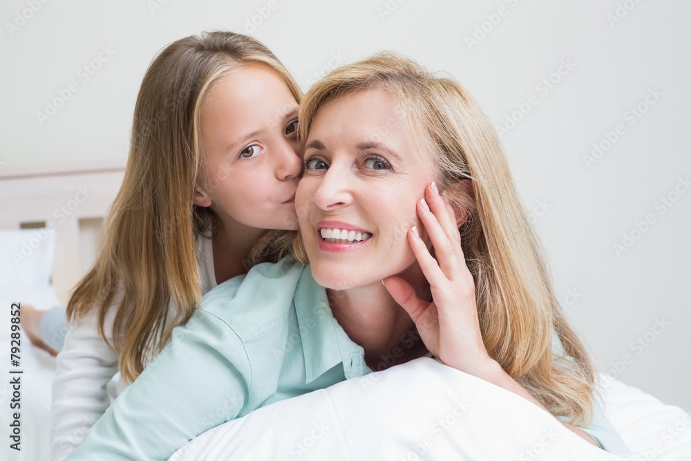 Cute girl kissing her smiling mother Cute girl kissing her smiling mother