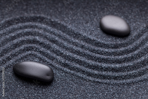 Zen garden with a wave lines in the sand with irregular black st