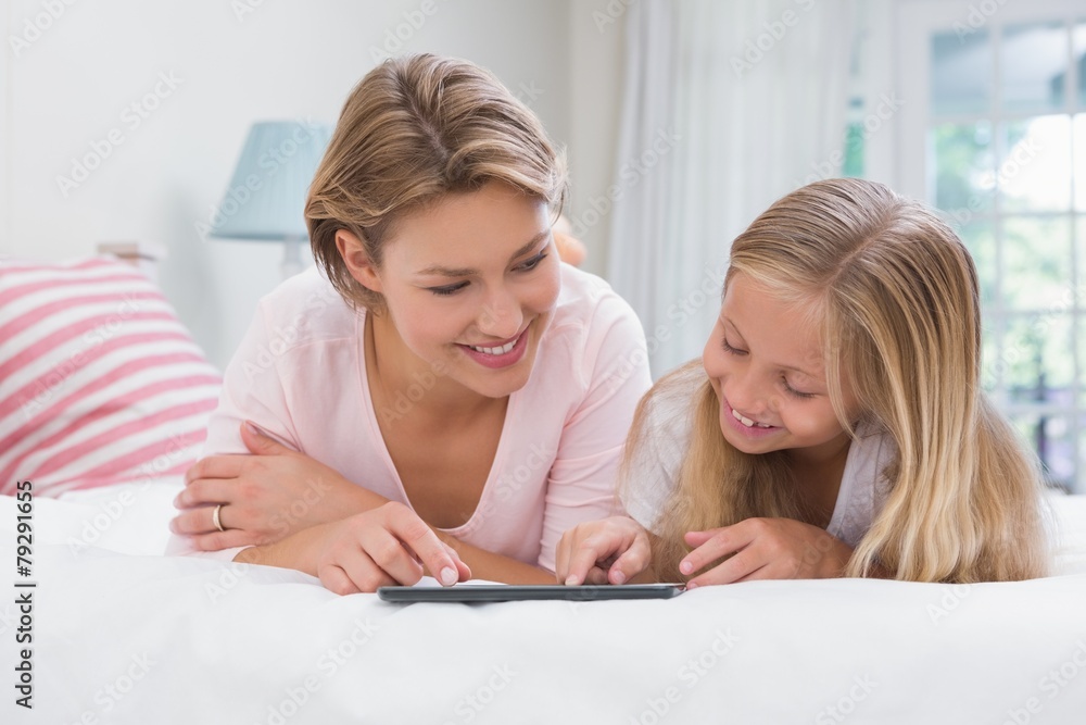 Mother and daughter using tablet together on bed Mother and daughter using tablet together on bed