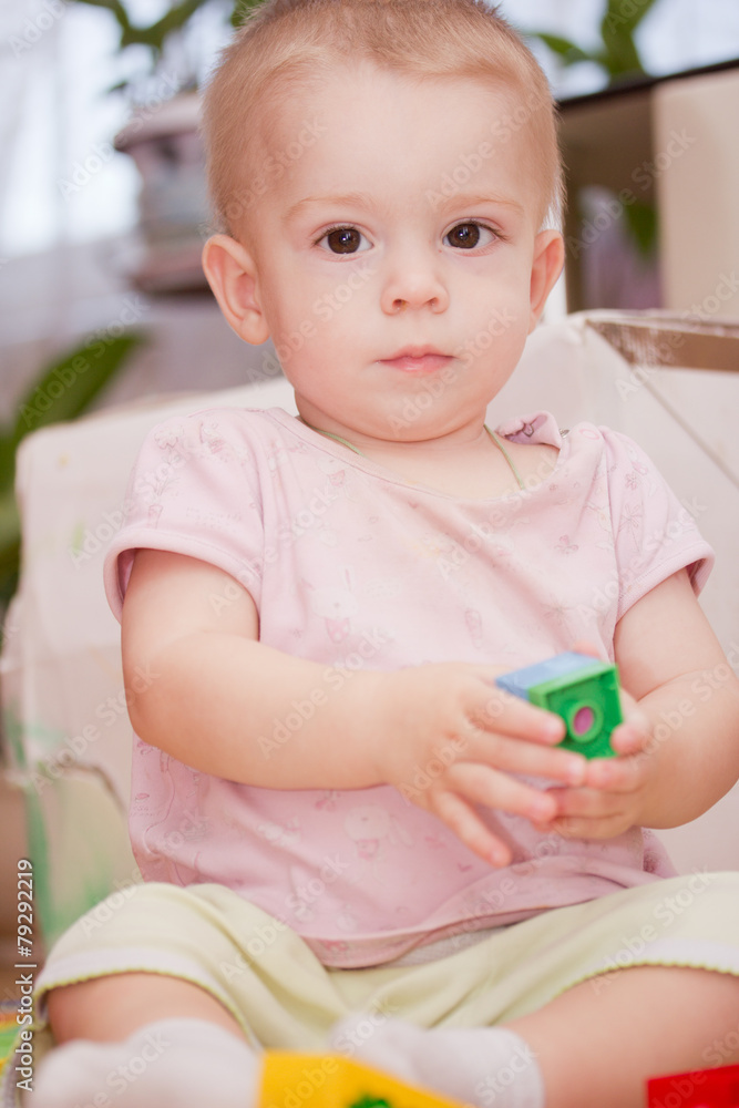 Cute little child is playing with toys while sitting on floor Cute little child is playing with toys while sitting on floor