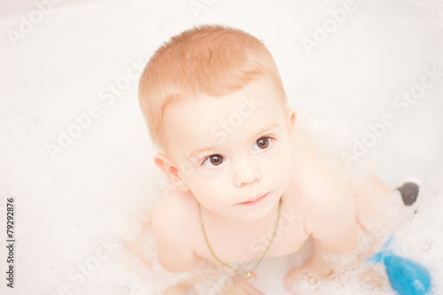 Happy baby in the bath, swimming in the foam.