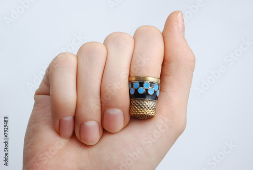 hand, a thimble on her finger