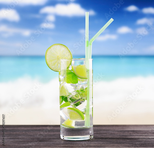 The glass of refreshing mojito cocktail on a beach