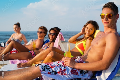 Friends sunbathing on a deck chairs on a beach © Nejron Photo