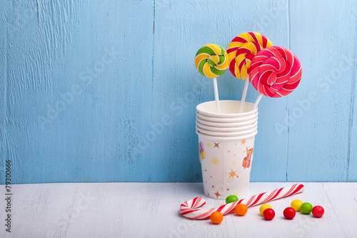 cups and lollipop on the blue wooden background