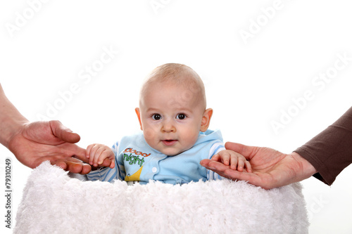 Uśmiechnięte niemowlę z dłońmi rodziców.