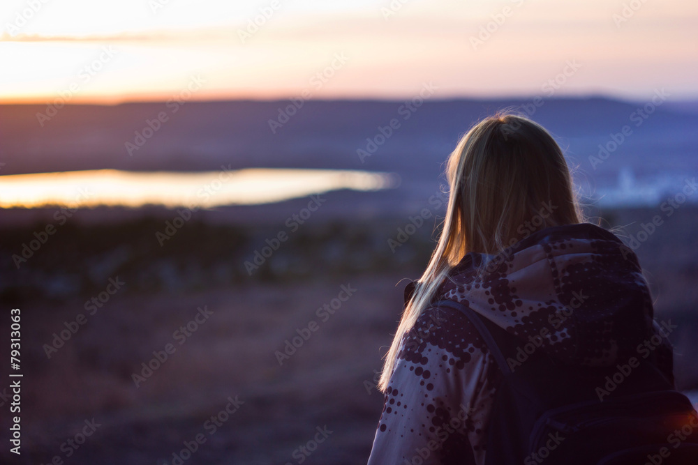 girl watching on a lake at sunset