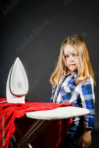 Cute little girl helping your mother by ironing clothes, contras