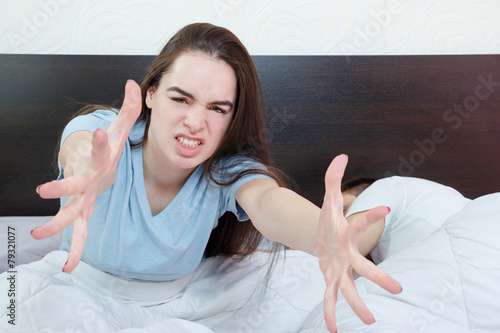 Dissatisfied beautiful young woman in bed asking for someone els photo