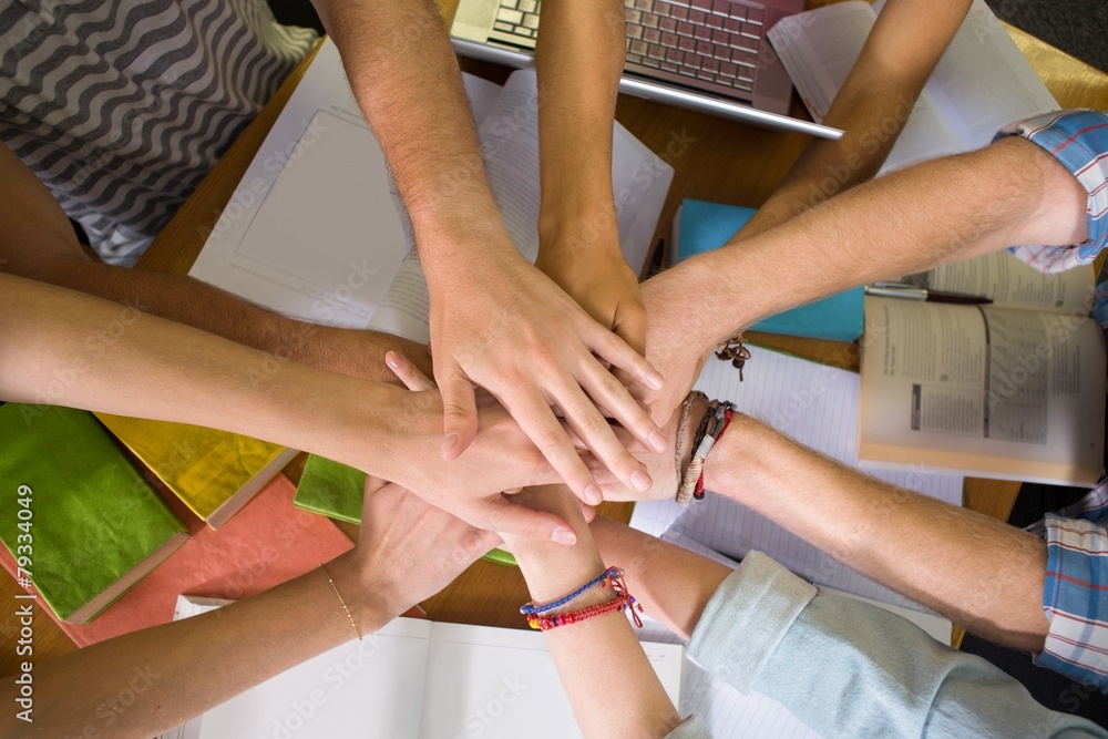 Obraz premium Students placing hands together over library table