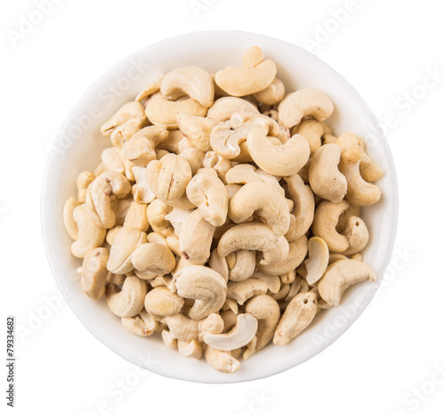 Raw cashew nuts in a white bowl over white background