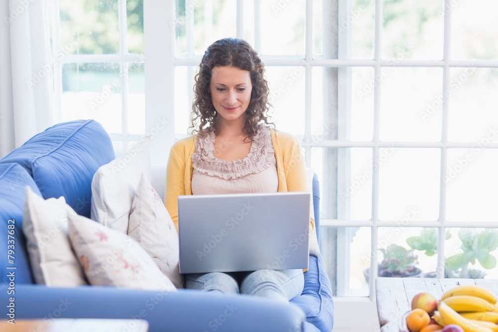Pretty brunette relaxing on the couch with laptop Pretty brunette relaxing on the couch with laptop