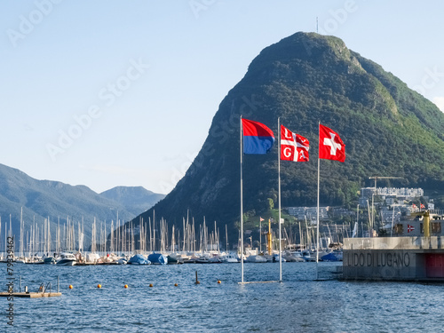 Fotografie Lake Lugano, Monte San Salvatore ,and the flags of Switzerland,