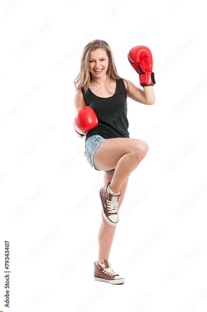 Young woman wearing boxing gloves and raising foot and hand Young woman wearing boxing gloves and raising foot and hand