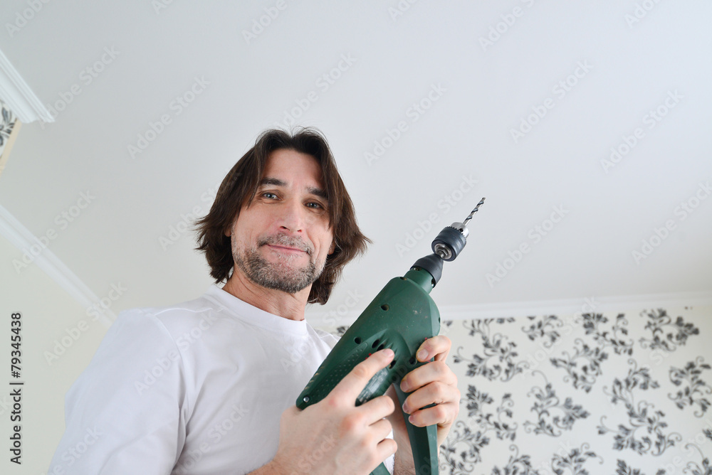 middle-aged man with a drill in hands of middle-aged man with a drill in hands of