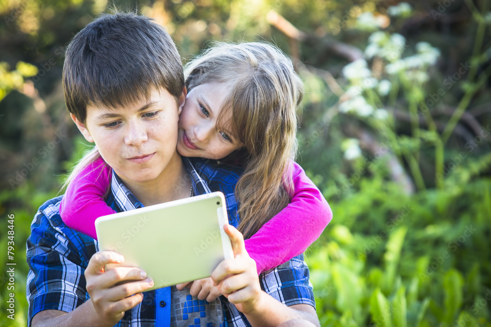 Teen boy with his younger sister sitting in a Park . Teen boy with his younger sister sitting in a Park .