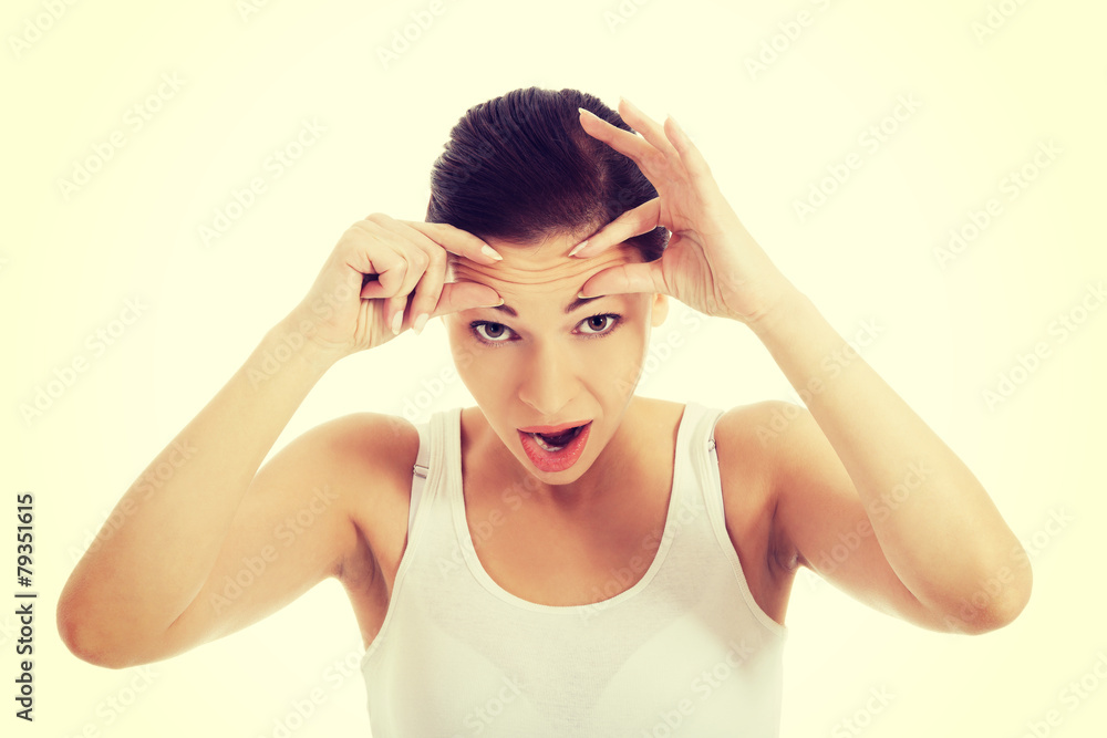 Young woman checking wrinkles on her forehead. Young woman checking wrinkles on her forehead.