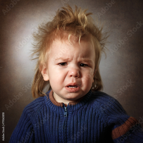 portrait of a frustrated baby on a dark background