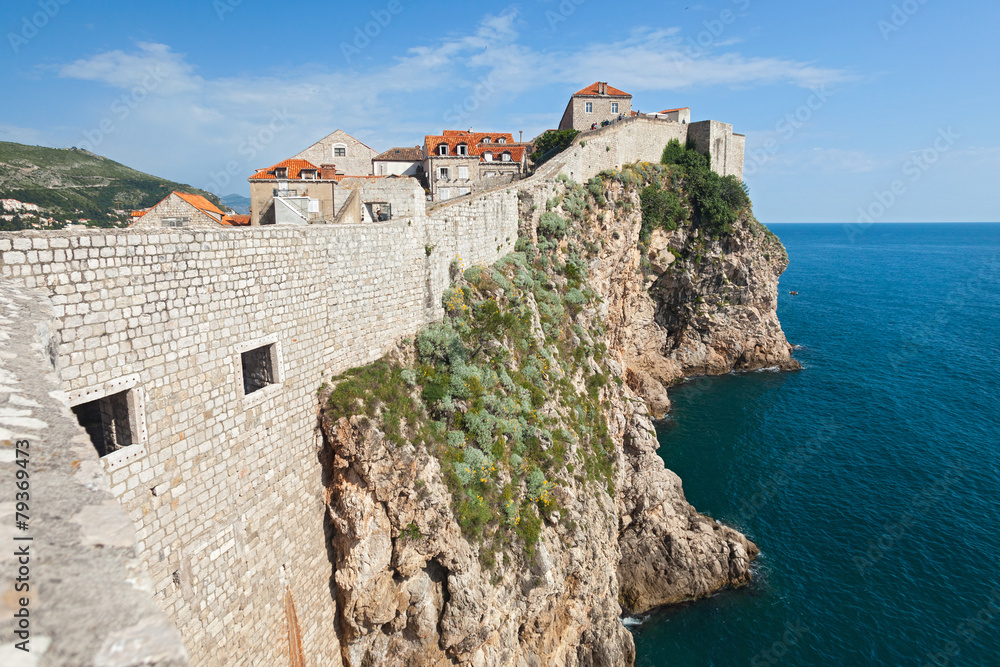 DUBROVNIK, CROATIA - MAY 26, 2014: Old city walls build on cliffs and houses inside the walls. City wall is one of most popular tourist attraction in Dubrovnik.