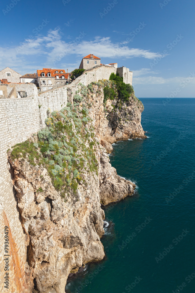 DUBROVNIK, CROATIA - MAY 26, 2014: Old city walls build on cliffs and houses inside the walls. City wall is one of most popular tourist attraction in Dubrovnik.