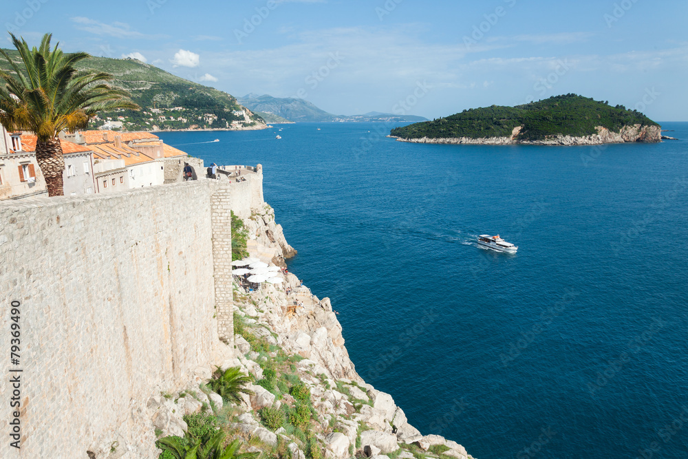 DUBROVNIK, CROATIA - MAY 26, 2014: Old city walls and Lokrum island. Old wall is one of Dubrovnik's most famous feature. It is almost 2 km long.