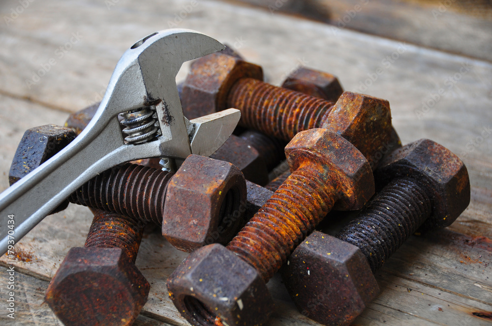Old bolts with adjustable wrench tools on wooden background. Old bolts with adjustable wrench tools on wooden background.