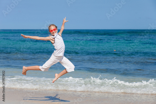 teen girl jumping on the beach at blue sea shore