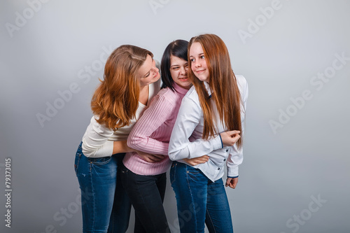 Three girls girlfriends European appearance in jeans hugging on