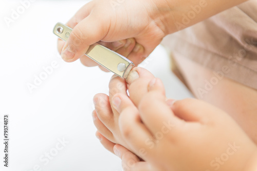 Little hand cutting his toenails on white background
