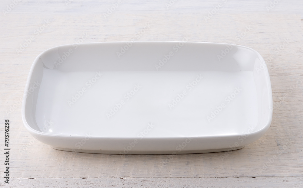 Empty white ceramic plate on wooden table Empty white ceramic plate on wooden table