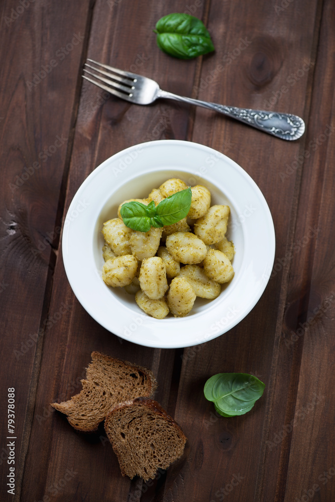 Italian gnocchi with basil pesto over dark wooden background Italian gnocchi with basil pesto over dark wooden background