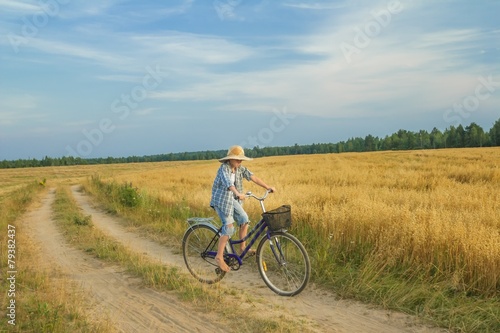 Teenager boy rides a bicycle on country road