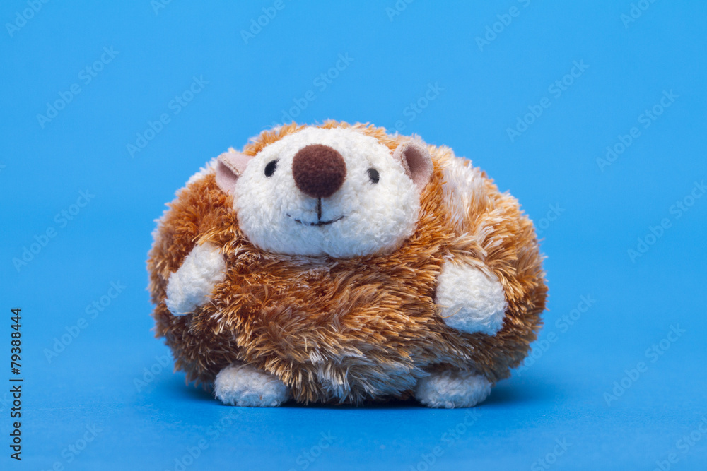 Fototapeta premium Cute small stuffed hedgehog toy over a blue background.