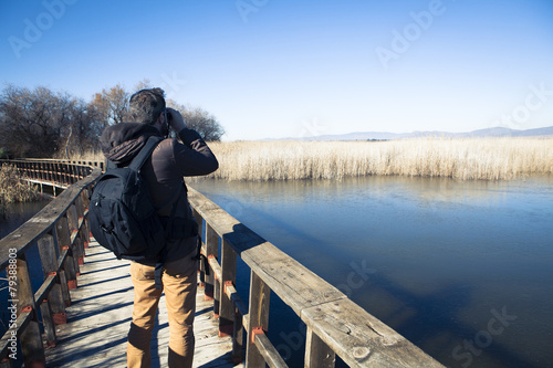 Man watching nature with binoculars, in a natural park. photo