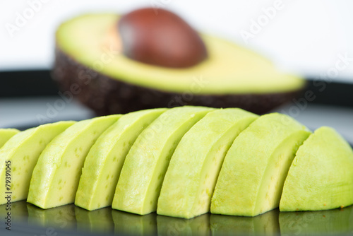 Slice avocado fruit on black dish