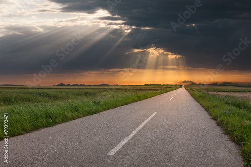 Φωτογραφία Driving on an empty country road at sunset
