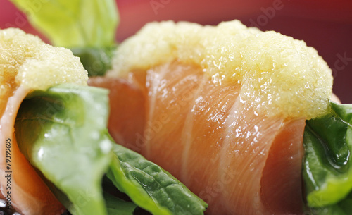 A close up of raw salmon sushi dish with rocket salad