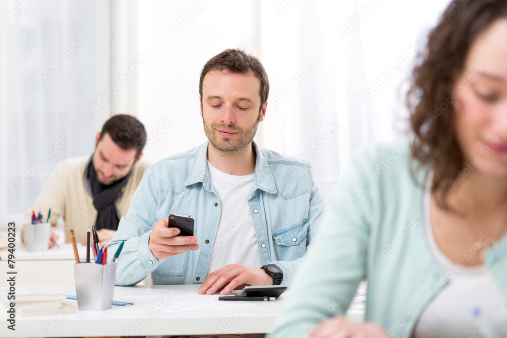 Young attractive student using his mobile during classes Young attractive student using his mobile during classes