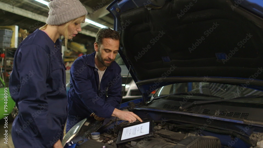 Car mechanic and a female trainee during a workshop using a digital tablet Car mechanic and a female trainee during a workshop using a digital tablet