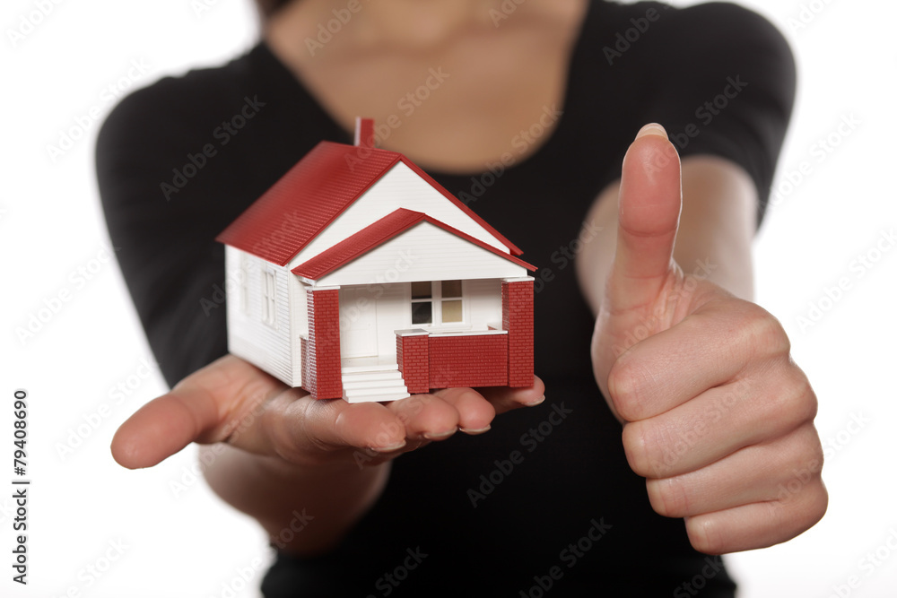Thumb up and miniature model house in woman hand