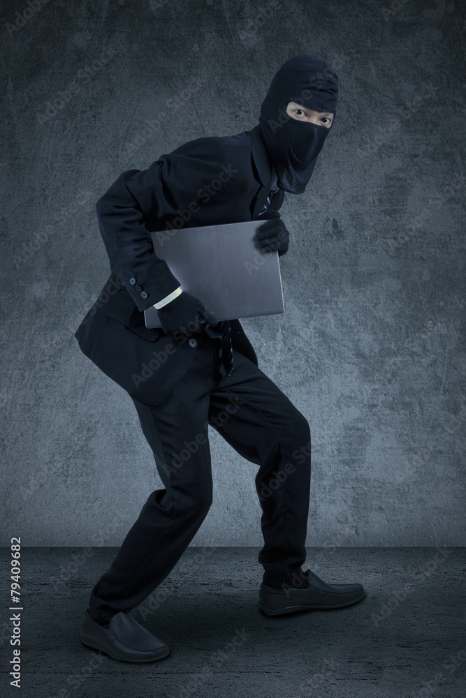 Manager with mask robbing a laptop Manager with mask robbing a laptop