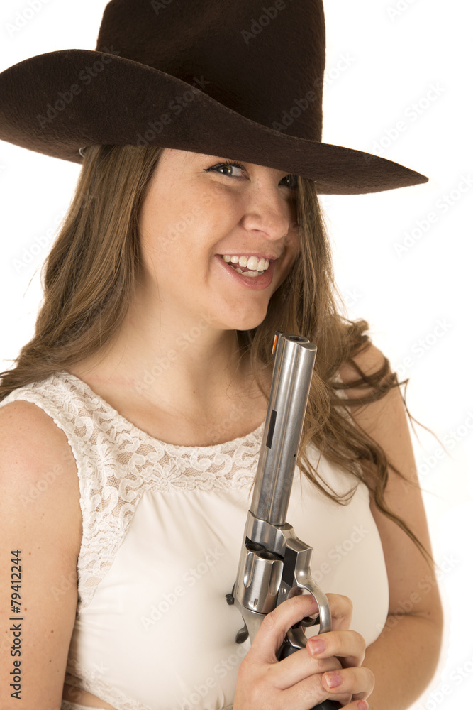 Cute cowgirl holding a big pistol looking forward laughing Cute cowgirl holding a big pistol looking forward laughing