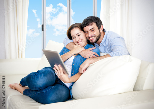 happy couple on home couch enjoying using digita tablet