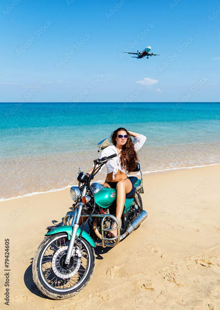 Obraz premium Young sexy girl in a bathing suit on a beach with the motorcycle