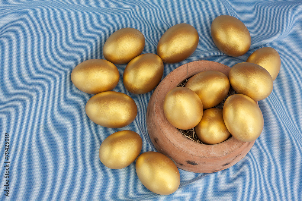 Stack of golden easter egg in baked clay bowl Stack of golden easter egg in baked clay bowl