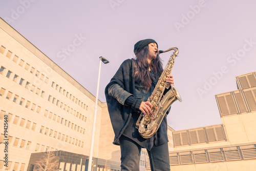Beautiful young woman playing tenor saxophone photo