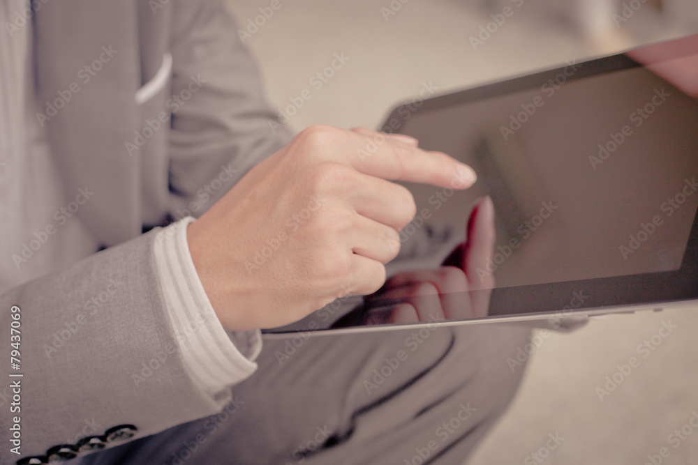 Businessman using electronic tablet pc. He is sitting on a stair