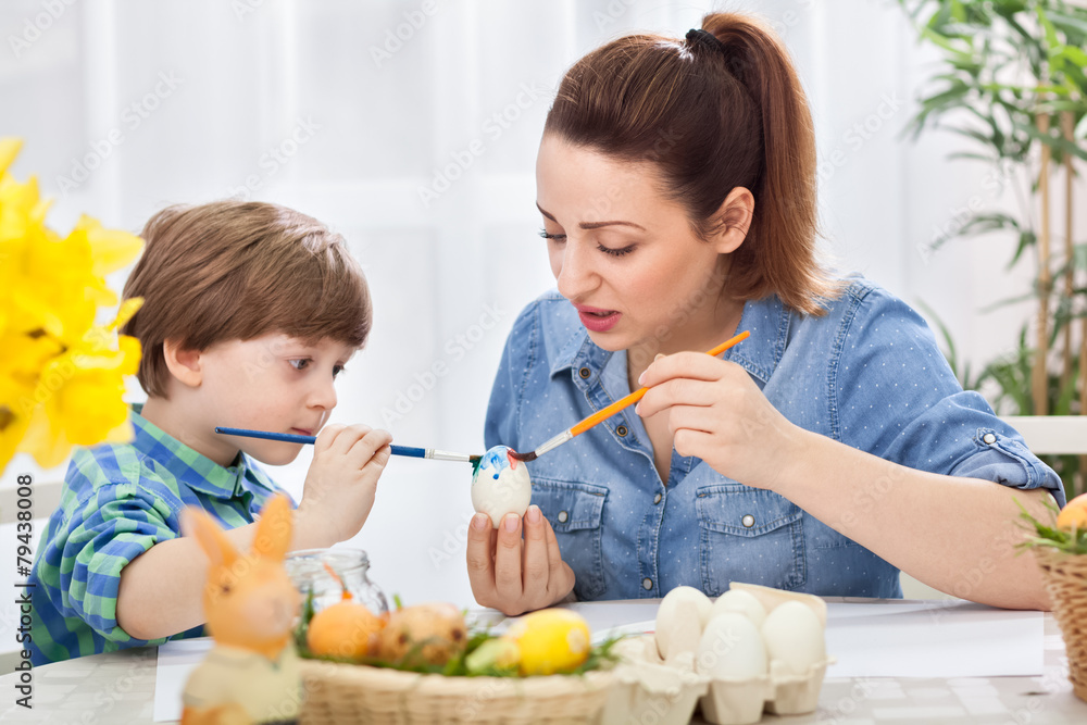 Young beautiful mother and her child painting together eggs for Young beautiful mother and her child painting together eggs for